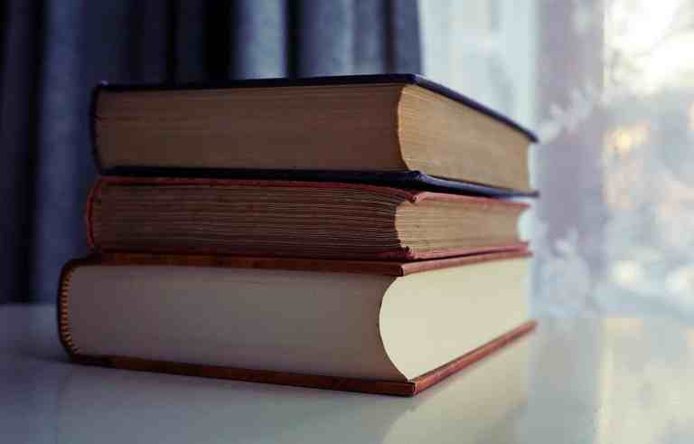 three piled books on white wooden table
